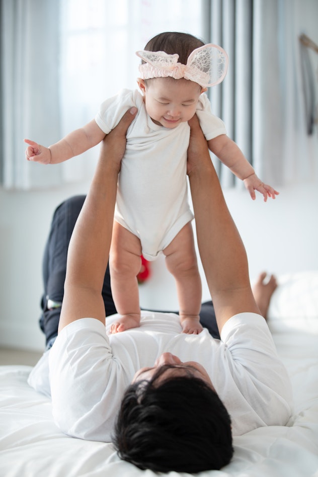 A father lifting his baby girl in the air while lying on his back