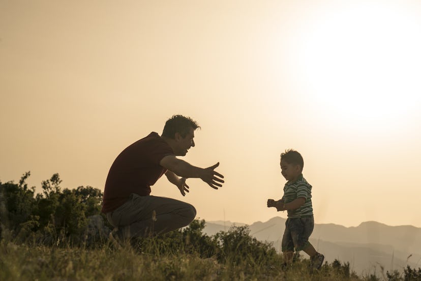 A small boy running into his father's hug in nature