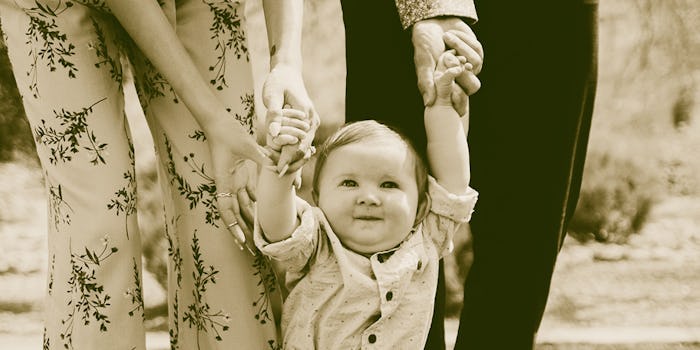 An adopted toddler walking while holding hands with parents