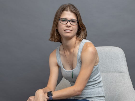 Jackie Noblett, struggling with Hypothalamic Amenorrhea, sitting in a grey top on a white chair