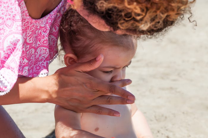 A mom applying sunscreen on her baby's face