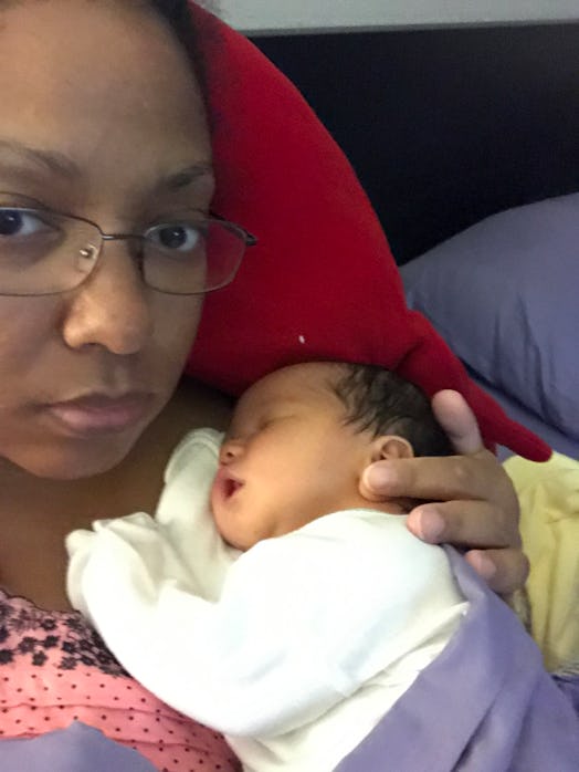 A mother taking a selfie while her newborn baby is sleeping on her chest