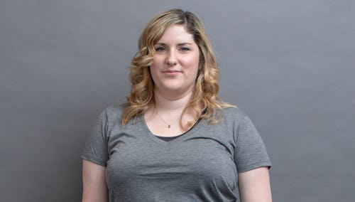 A woman with PCOS posing in a grey shirt in front of a grey background