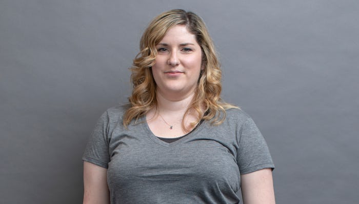 A woman with PCOS posing in a grey shirt in front of a grey background