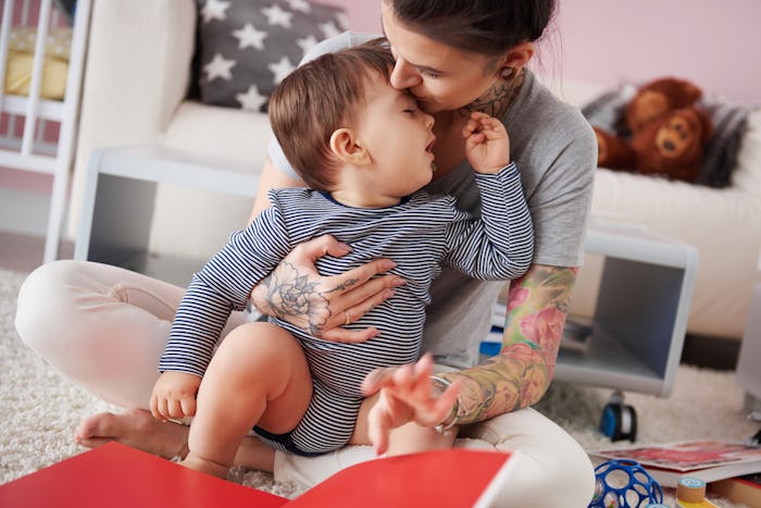 An exhausted mom kissing her baby boy