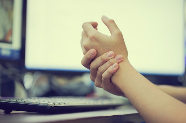 close up of hands massaging themselves at a computer desk