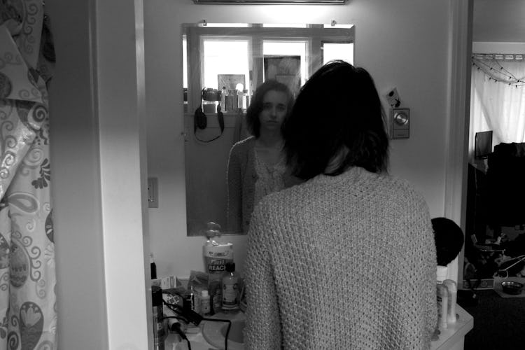 A woman with endometriosis looking herself in the mirror