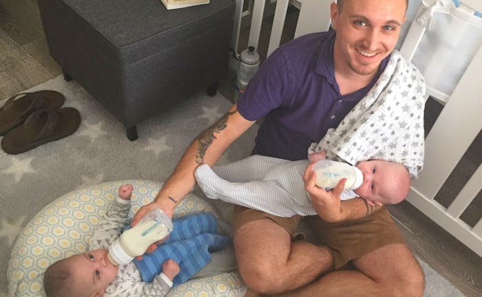 A male doula feeding two babies while holding one and the other lays on a pillow