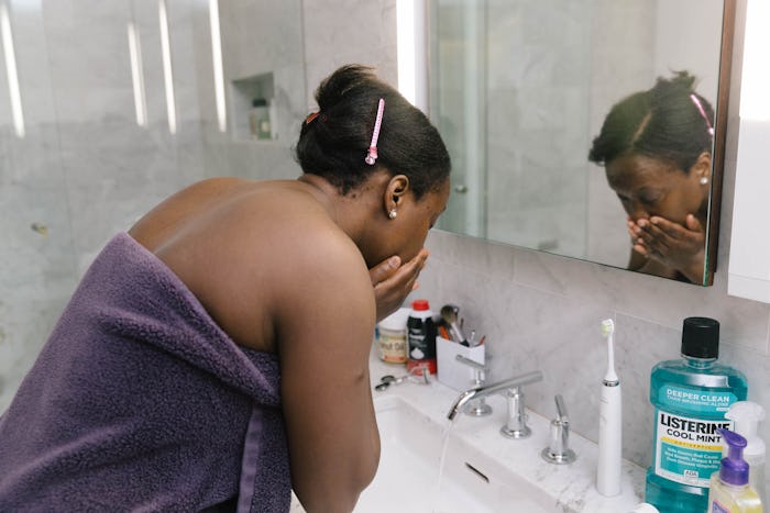 Woman washes face in bathroom.