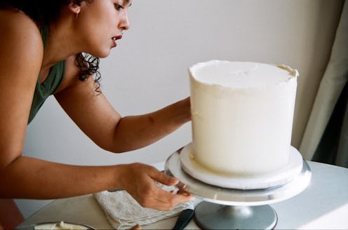 A woman decorating a white one-tier wedding cake