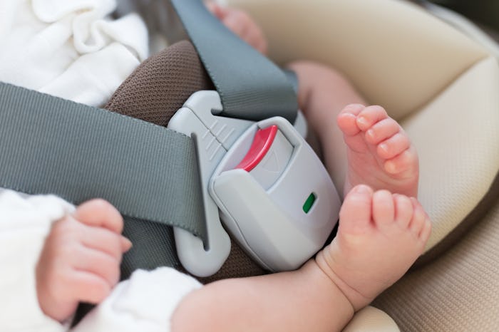 A little barefoot baby sitting in a car seat