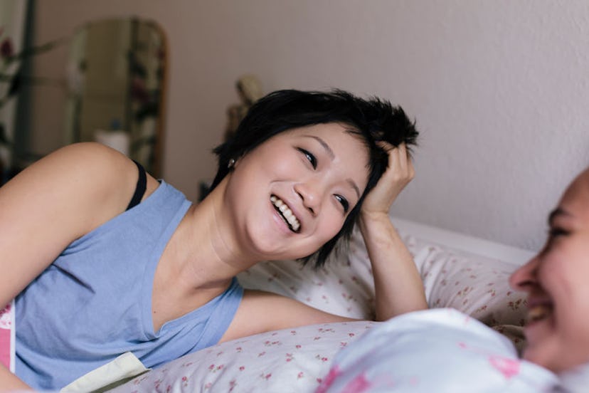 Two women laughing in bed