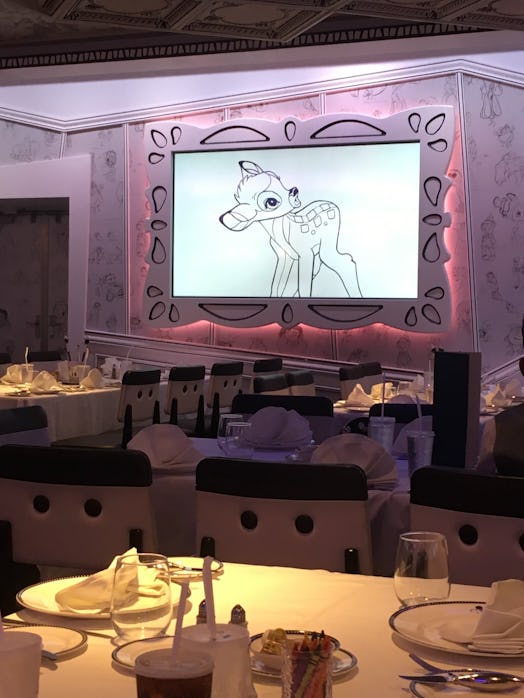 A restaurant where everything's prepared for dinner where a cartoon - Bambi is playing on the screen
