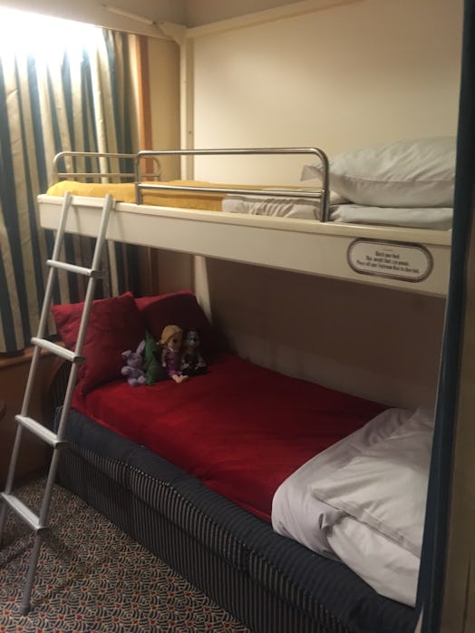 A room on the cruise, with a bunk bed having yellow and red sheets