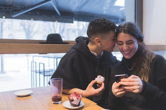 A couple eating cupcakes and laughing in a cafe