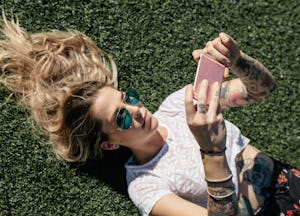A girl lying on grass and looking at social media on her phone
