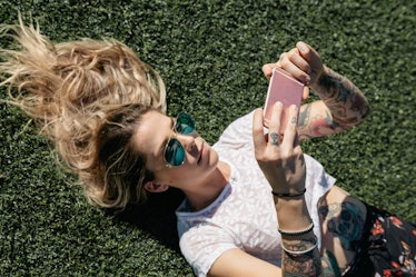 A girl lying on grass and looking at social media on her phone