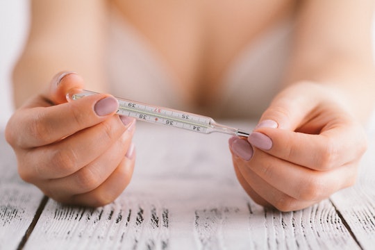Woman in bra looking at her thermometer to check her temperature rise