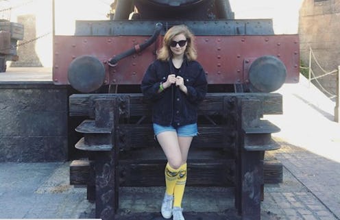 Young blonde lady posing in front of a locomotive statue