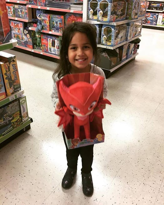 A little girl holding the red colored toy in a toys store smiling and posing for a pic