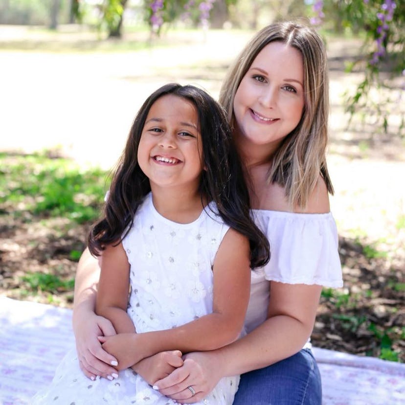 A mother and a daughter hugging and holding hands while posing for a picture