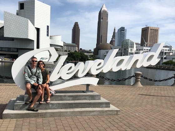 A couple sitting in front of the Cleveland sign