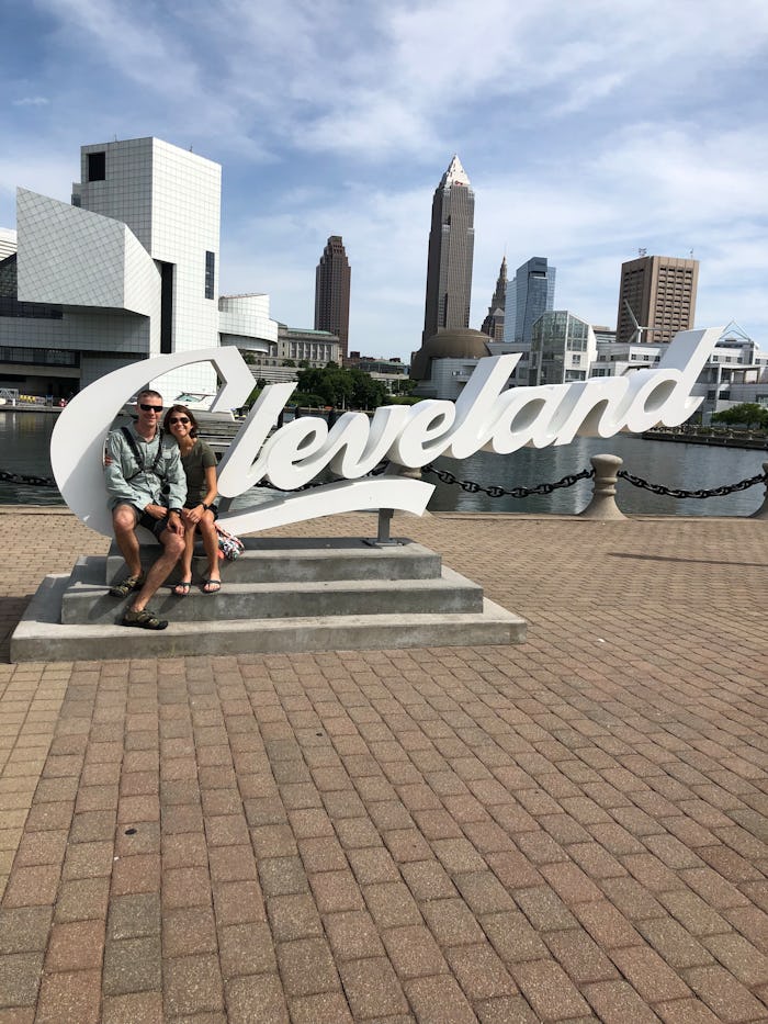 A couple sitting in front of the Cleveland sign