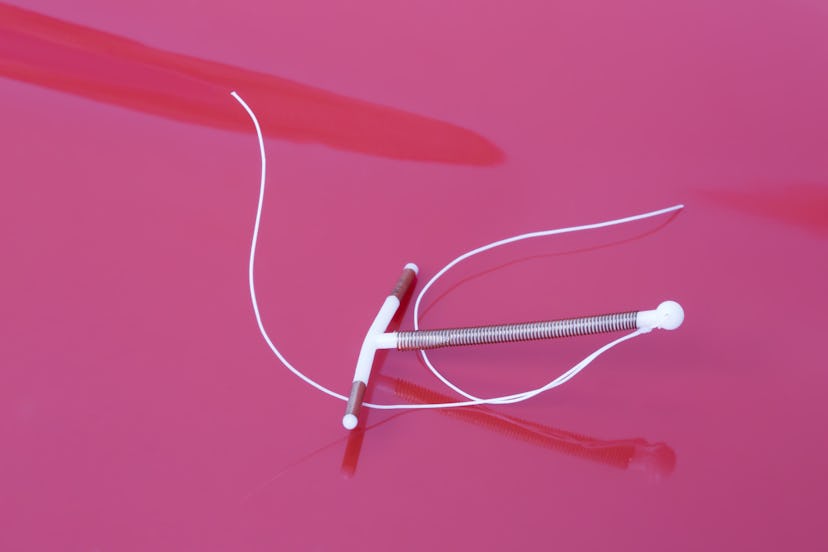 Eco-conscious form of birth control, intrauterine device (IUD) in front of a pink background