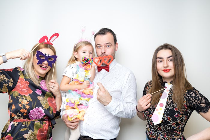 Parents holding their child, dressed in fun evening wear with accessories for taking pictures