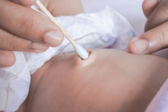 hands cleaning bellybutton of newborn with q tip