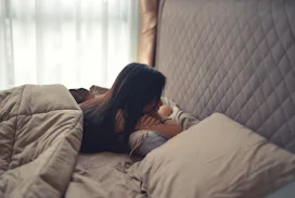 A woman lying stomach-down in her bad and has an eating disorder