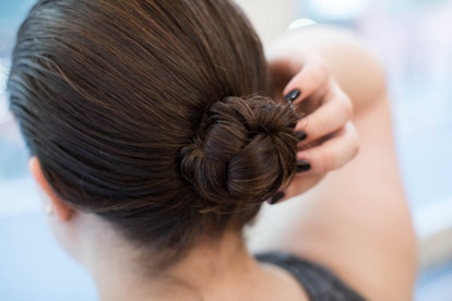 A brunette woman checking her hair bun