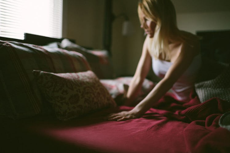 A woman sitting on her bed, frustrated because of sleep issues caused by her depression