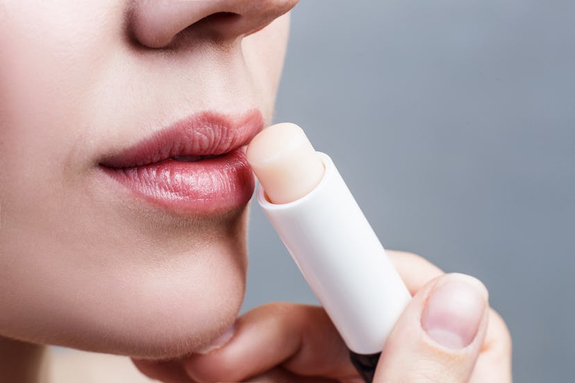 A woman applying a balm with SPF on her lips