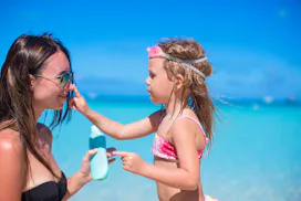 A little girl putting sunscreen on the nose of her mother