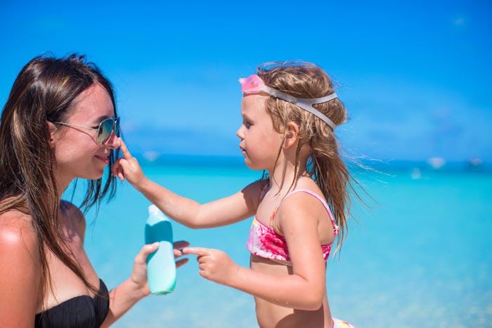 A little girl putting sunscreen on the nose of her mother