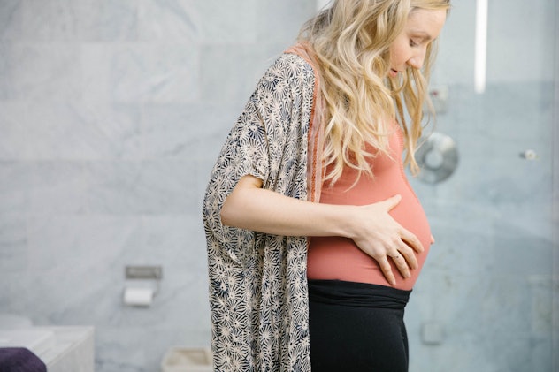 A pregnant woman with PCOS holding her belly