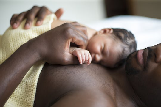 A feminist man lying on his back with his newborn on his chest