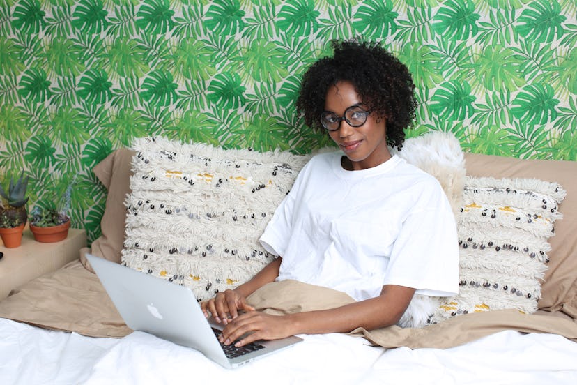 A woman in bed searching doctors on her laptop