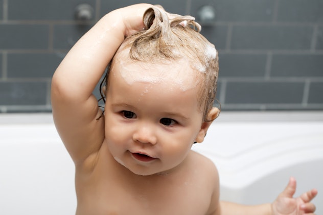 A baby in the bathtub with shampooed hair.