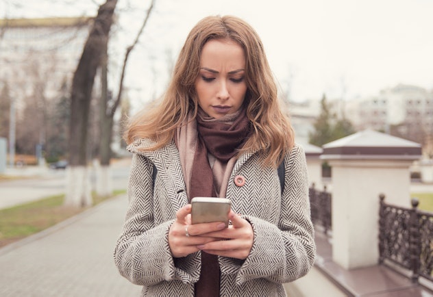 A woman looking at her iphone, looking upset. 