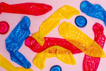 Blue, red, and yellow used condoms on a pink platform