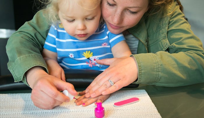 Mother helping young child paint nails pink