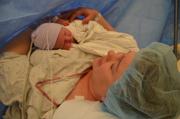 A mother lying in hospital while holding her newborn baby