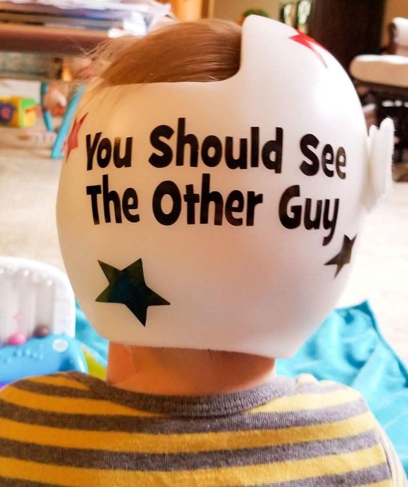 A baby boy wearing a helmet with "you should see the other guy" text
