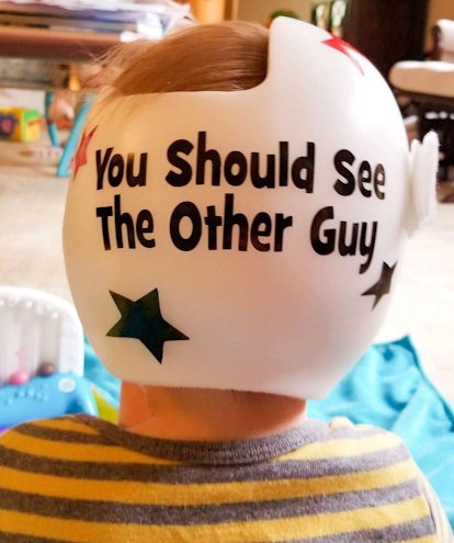 A baby boy wearing a helmet with "you should see the other guy" text