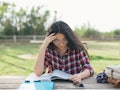 A college student studying while holding her head because of migraine pain