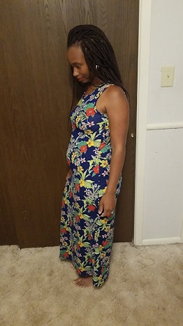 A pregnant woman is standing in a room wearing a colorful dress.