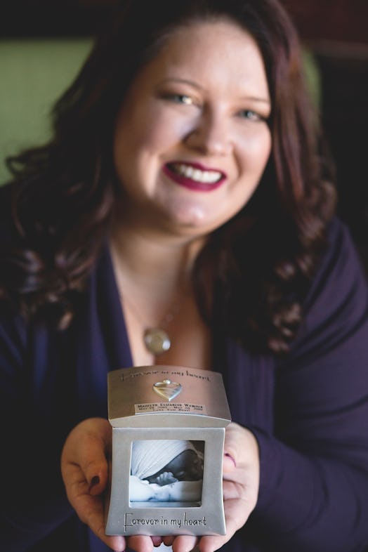 A close-up of a woman holding a picture frame with her newborn's picture.
