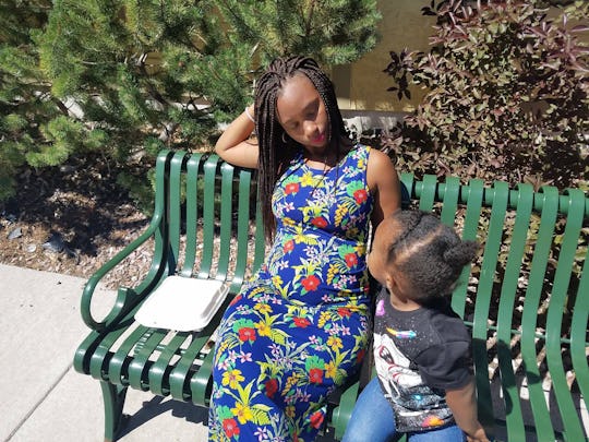 Rochaun Meadows-Fernandez sitting on a park bench with her child on a sunny day